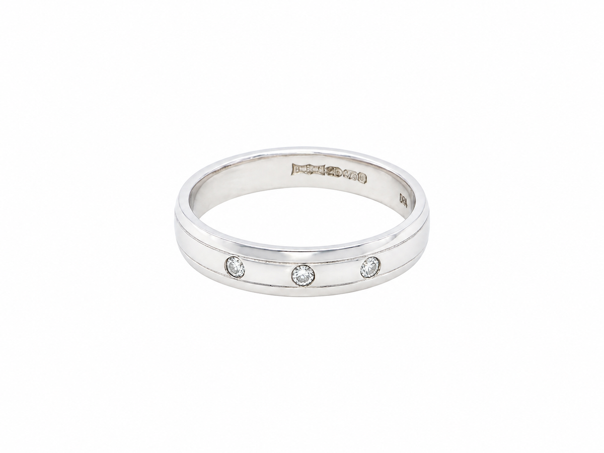 A 9 carat white gold wedding ring. Set with three invisbly set diamonds, each 1.5mm (0.015 carats each).