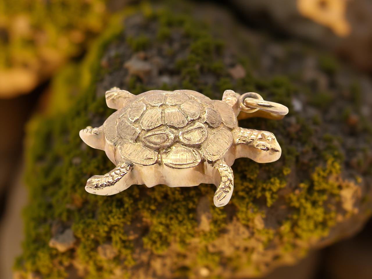 Gold turtle pendant on a textured green surface