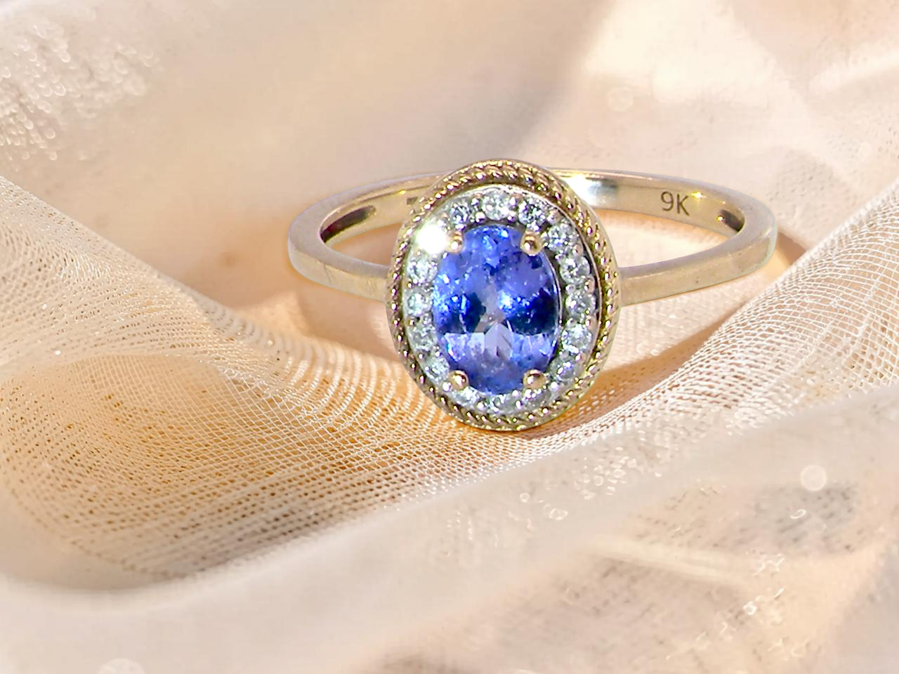 A 9 carat gold cluster ring. Features to the centre an oval cut tanzanite gem stone. Measures 7x5mm,  claw setting.