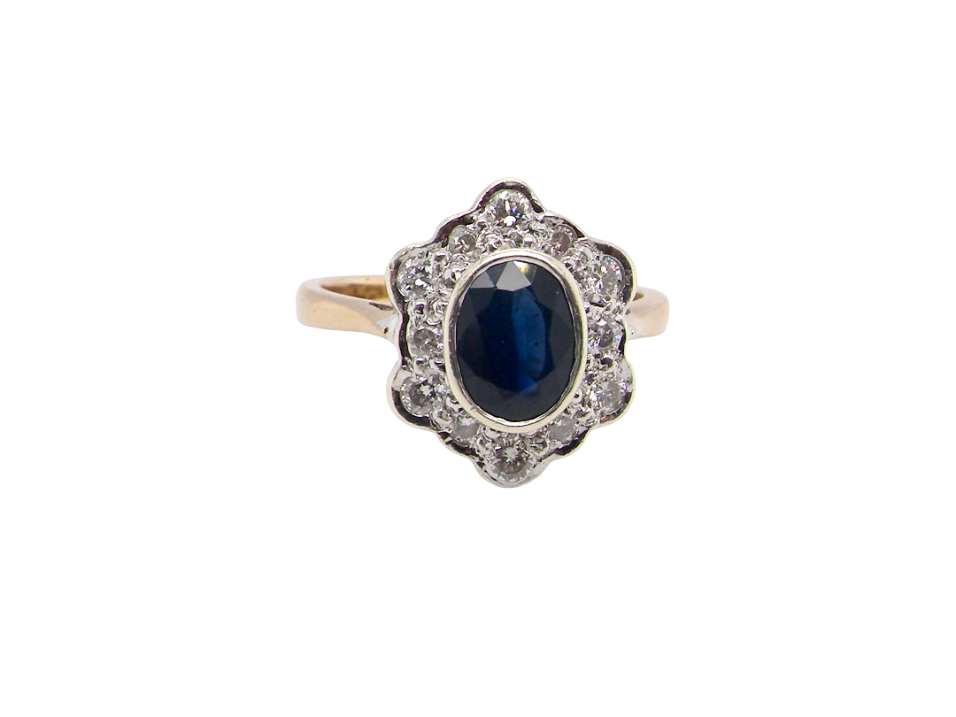 A 9 carat gold cluster ring that features an inky black blue oval cut sapphire. This measures 8x6mm 