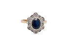 A 9 carat gold cluster ring that features an inky black blue oval cut sapphire. This measures 8x6mm 