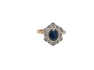 A 9 carat gold cluster ring that features an inky black blue oval cut sapphire. This measures 8x6mm in a safe rim style setting 