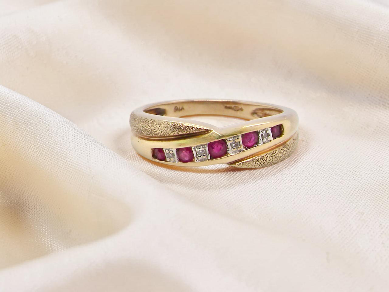 A 9 carat gold half hoop eternity ring. Set with five calibre cut rubies, from 1.7 to 2mm, and between 1mm white diamonds.
