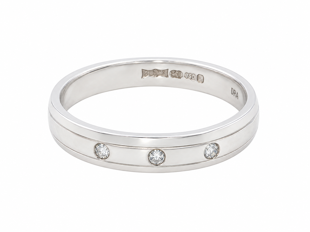 band ring with three small round-cut clear gemstones set in a row, photographed on a clean white background.