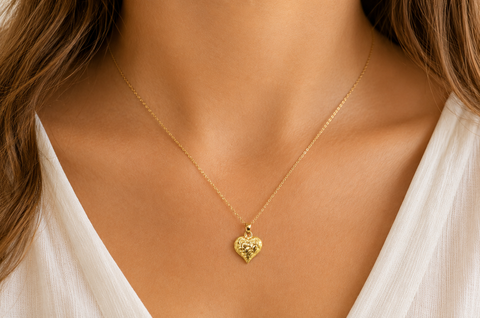 A 9ct gold patterned heart pendant on female