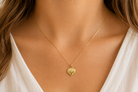 A 9ct gold patterned heart pendant on female