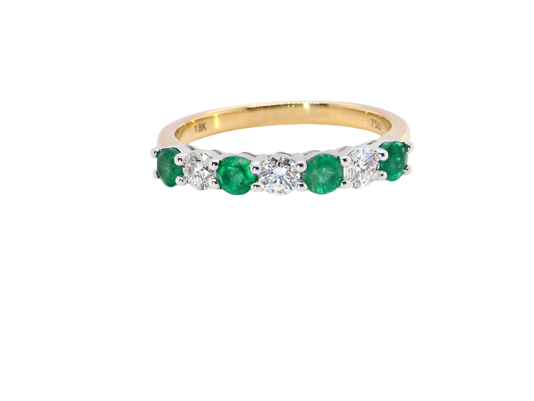 A NEW seven stone half hoop eternity ring. Set with four round emeralds, (total 0.40 carats)