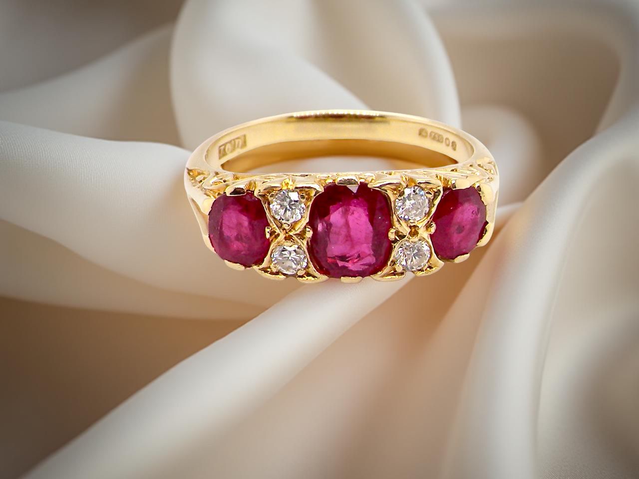 Gold ring with ruby gemstones and small diamonds on a soft white background