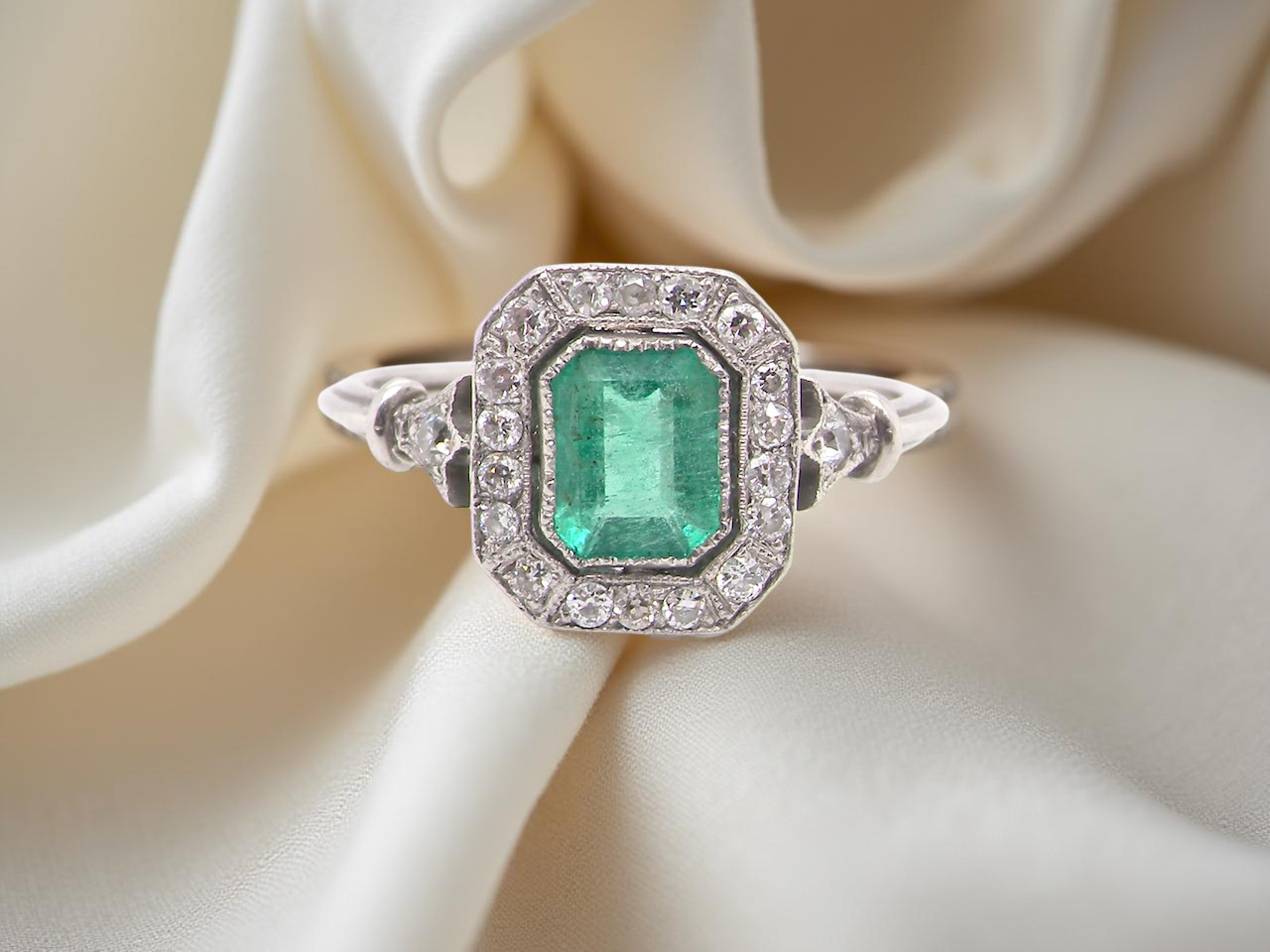 A beautiful Art Deco cluster ring centred with a step-cut emerald