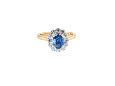 A beautiful cluster ring featuring an oval-cut mid to dark blue sapphire measuring 7 × 5 mm (approximately ¾ carat).