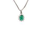 A beautiful traditional cluster pendant featuring a vibrant oval-cut emerald 