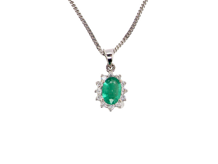 A beautiful traditional cluster pendant featuring a vibrant oval-cut emerald 