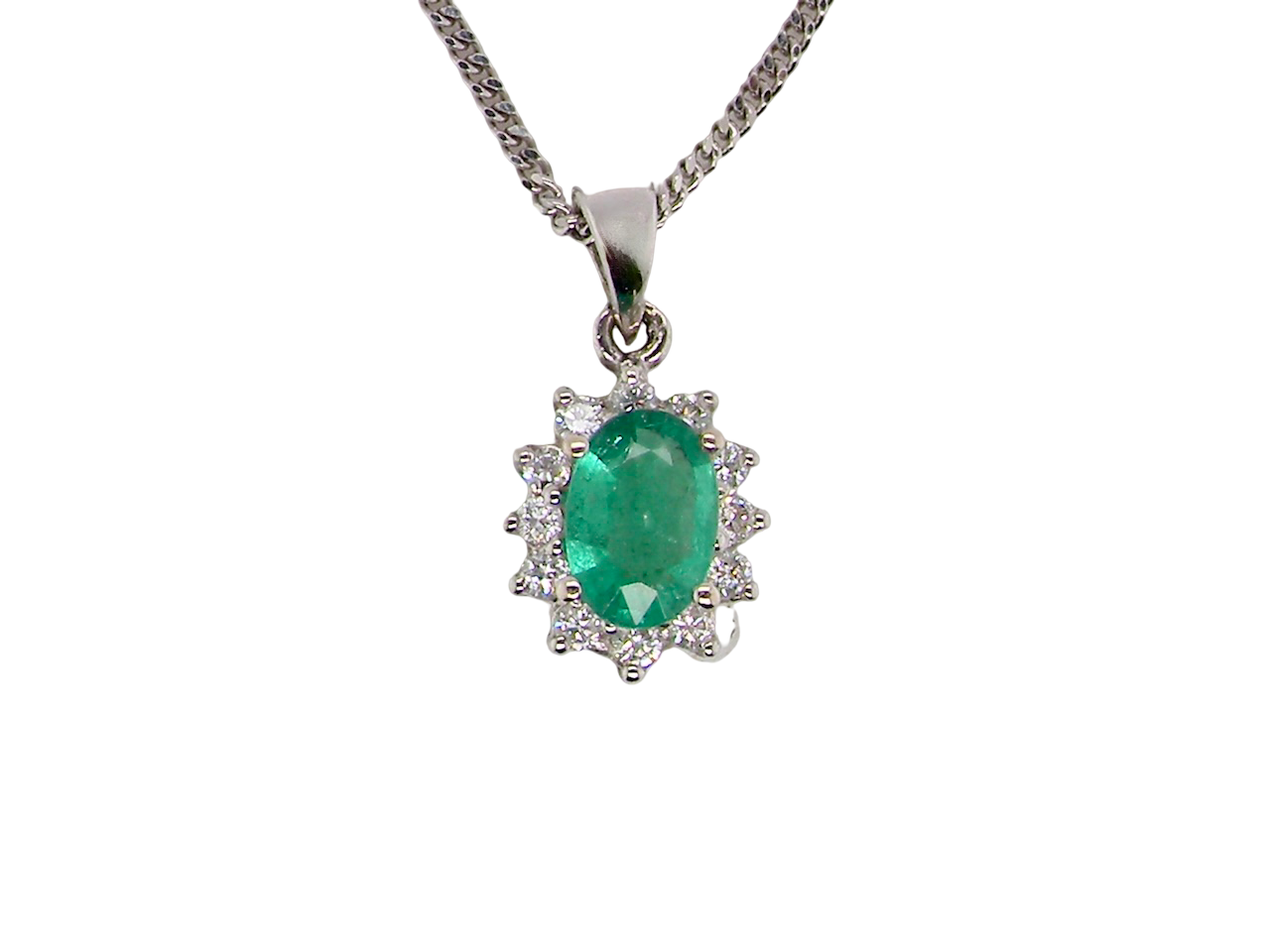 A beautiful traditional cluster pendant featuring an oval-cut emerald 