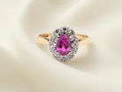 A beautiful vintage cluster ring showcasing a vivid pink sapphire centre stone, measuring approximately 6.6 × 4.3 mm