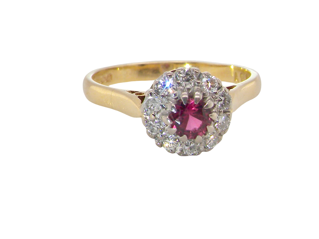 A yellow gold ring featuring a central round pink gemstone surrounded by a halo of small clear stones, set against a plain white background.