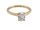 A yellow gold solitaire ring featuring an oval-cut clear gemstone in a four-prong setting, shown against a plain white background.
