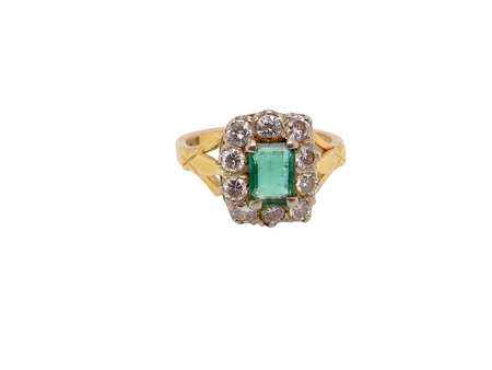 A cluster ring that features a rectangular emerald centre stone, 7x5mm . Deep green colour, natural inclusions that can be seen under an eye glass,