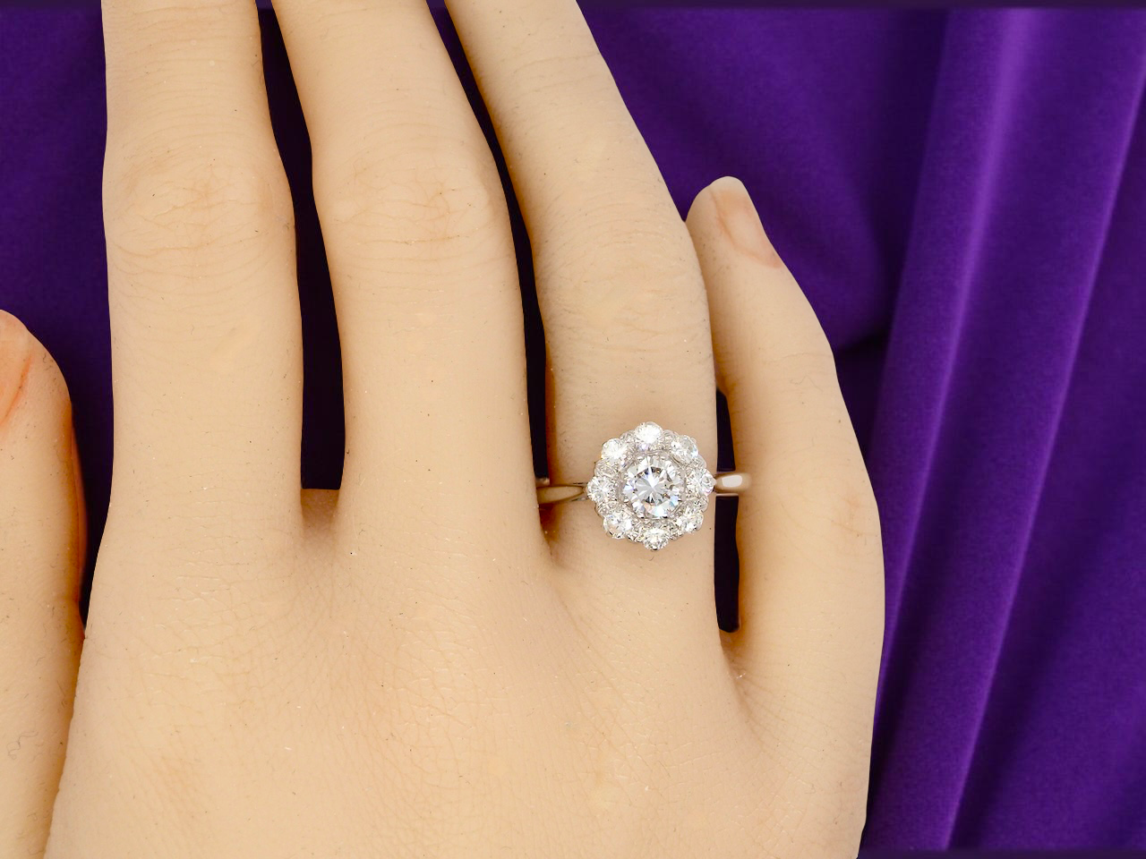 Diamond ring on a hand with a purple fabric background