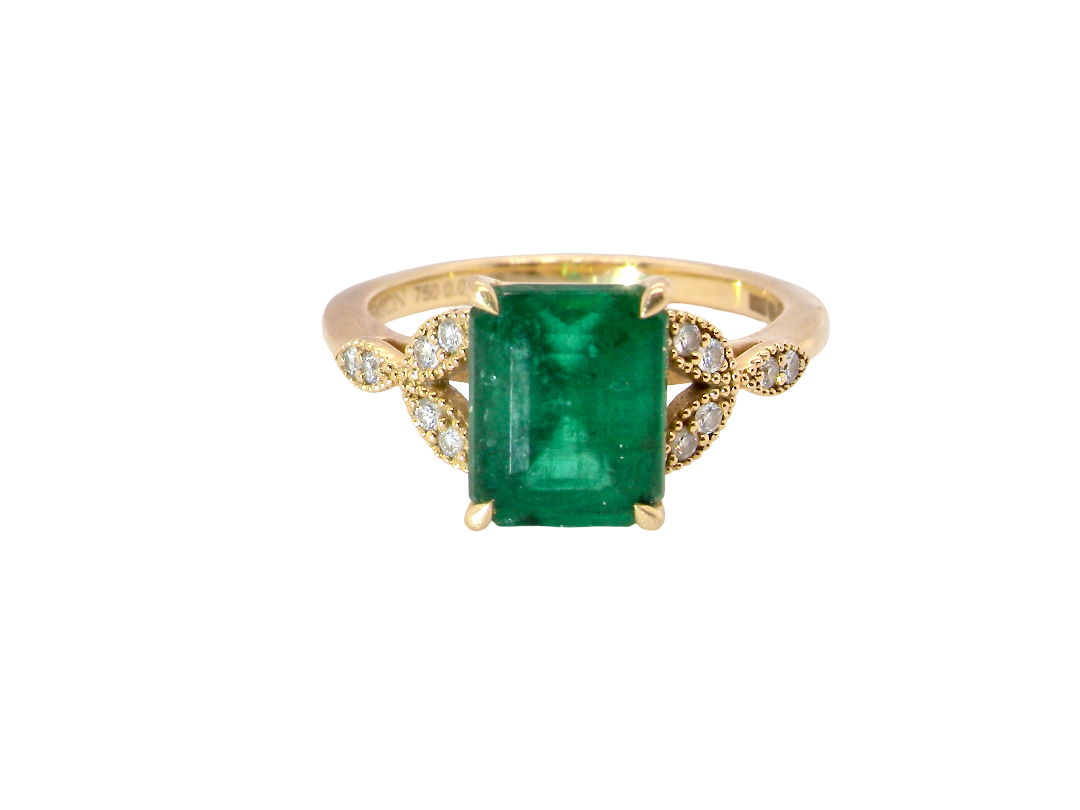 A yellow gold ring featuring a rectangular emerald-cut green gemstone, accented by small clear stones on the shoulders, set against a plain white background.