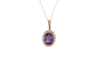 An oval pendant necklace featuring a central purple amethyst gemstone surrounded by a halo of small clear stones, set in yellow gold and suspended from a delicate gold chain against a plain white background.
