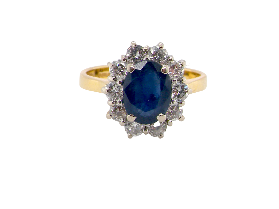 A yellow gold ring featuring an oval-cut deep blue sapphire center stone surrounded by a halo of small clear diamonds, set against a plain white background.