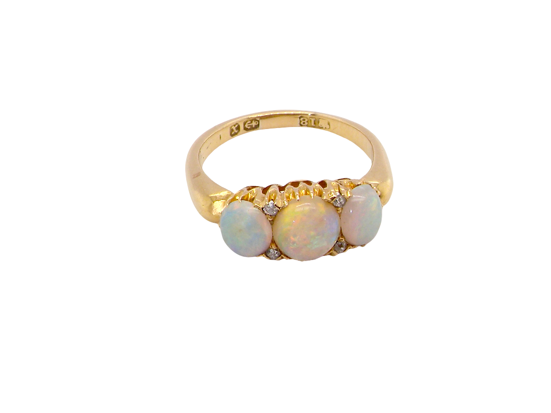 A yellow gold ring featuring three round iridescent white opal gemstones and small clear accent stones, shown on a plain white background.