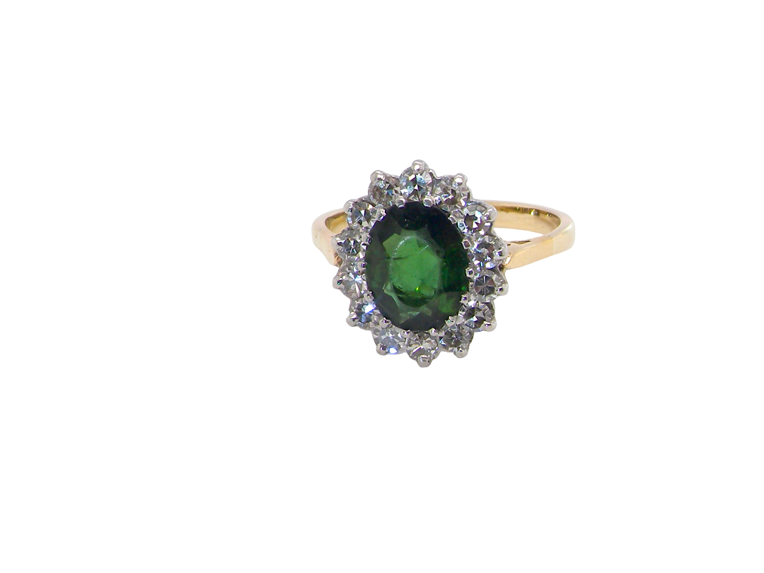 A fine and impressive vintage cluster ring, centred with a striking oval-cut deep dark green tourmaline, measuring 9 x 7mm and estimated to weigh approximately 2.00 carats.