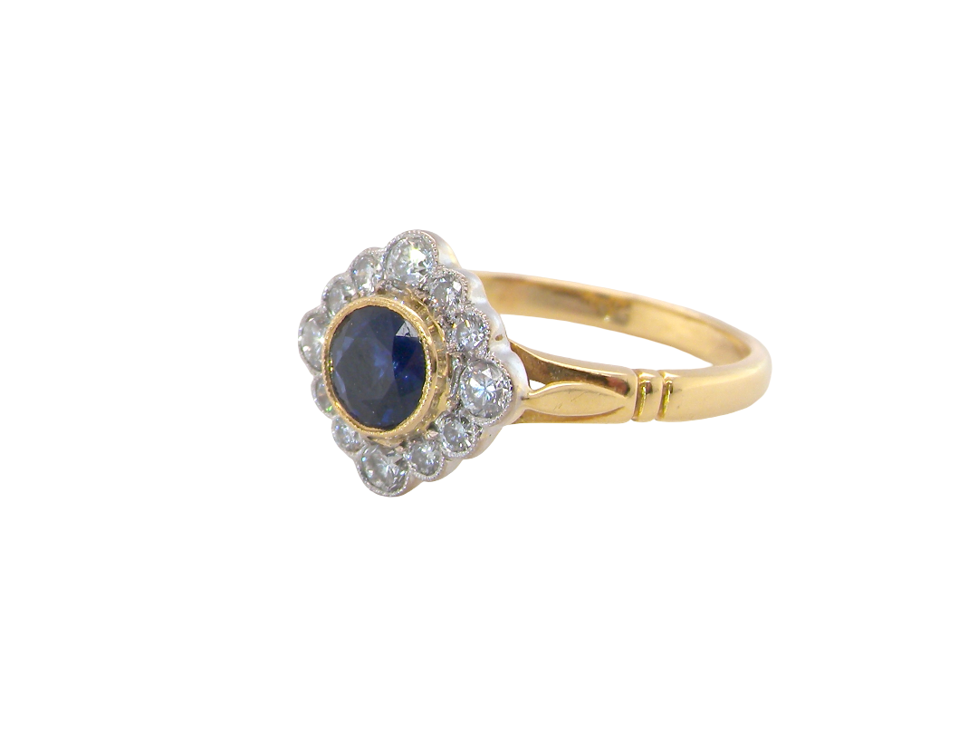 A fine cluster ring featuring to the centre a round dark blue sapphire, 5mm diameter (0.50 carats) 

