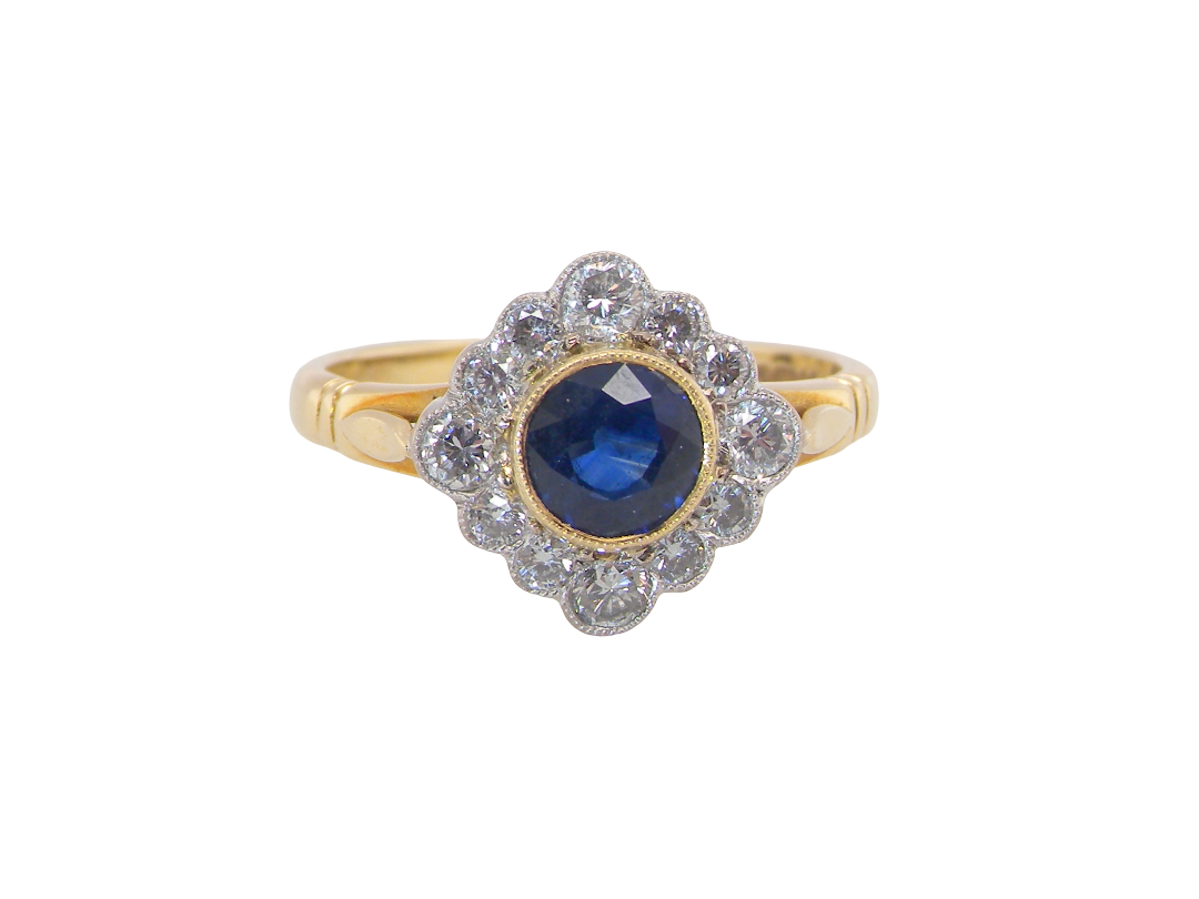A fine cluster ring featuring to the centre a round dark blue sapphire, 5mm diameter  mille grain setting.
