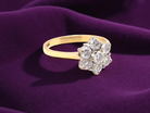 Gold ring with diamond cluster on a purple fabric background