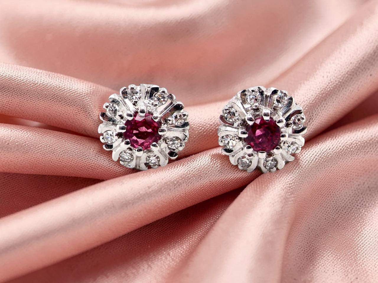 A fine pair of cluster earrings. Features to the centre a round 4.6mm pink sapphire  with a good deep colour hue.