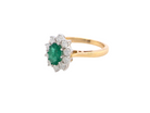 A fine traditional emerald and diamond cluster ring, featuring a vibrant oval-cut emerald to the centre measuring approximately 7 × 5 mm  side