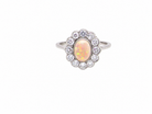 A fine vintage cluster ring. Features to the centre an oval shaped opal, with excellent play of colour, pink to one way, vibrant green to the other with flashes of electric blue also within the body of the gem.
