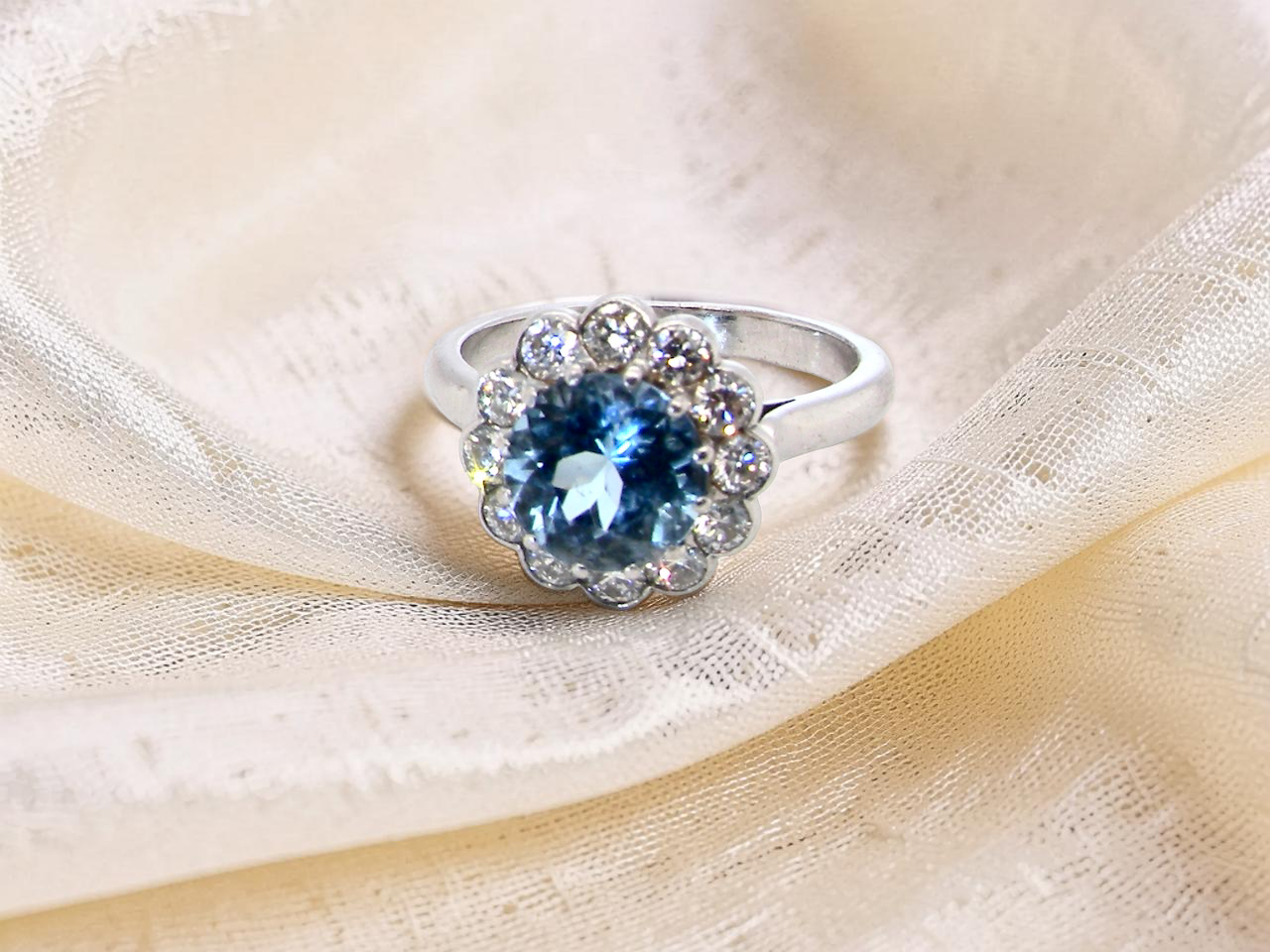 A fine vintage cluster ring centred with a deep blue aquamarine, measuring approximately 8mm and estimated at 2 carats, 