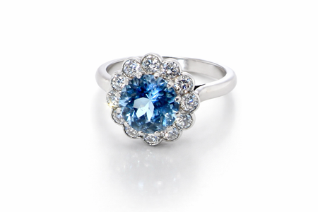 A fine vintage cluster ring centred with a deep blue aquamarine, measuring approximately 8mm and estimated at 2 carats, securely claw set.
