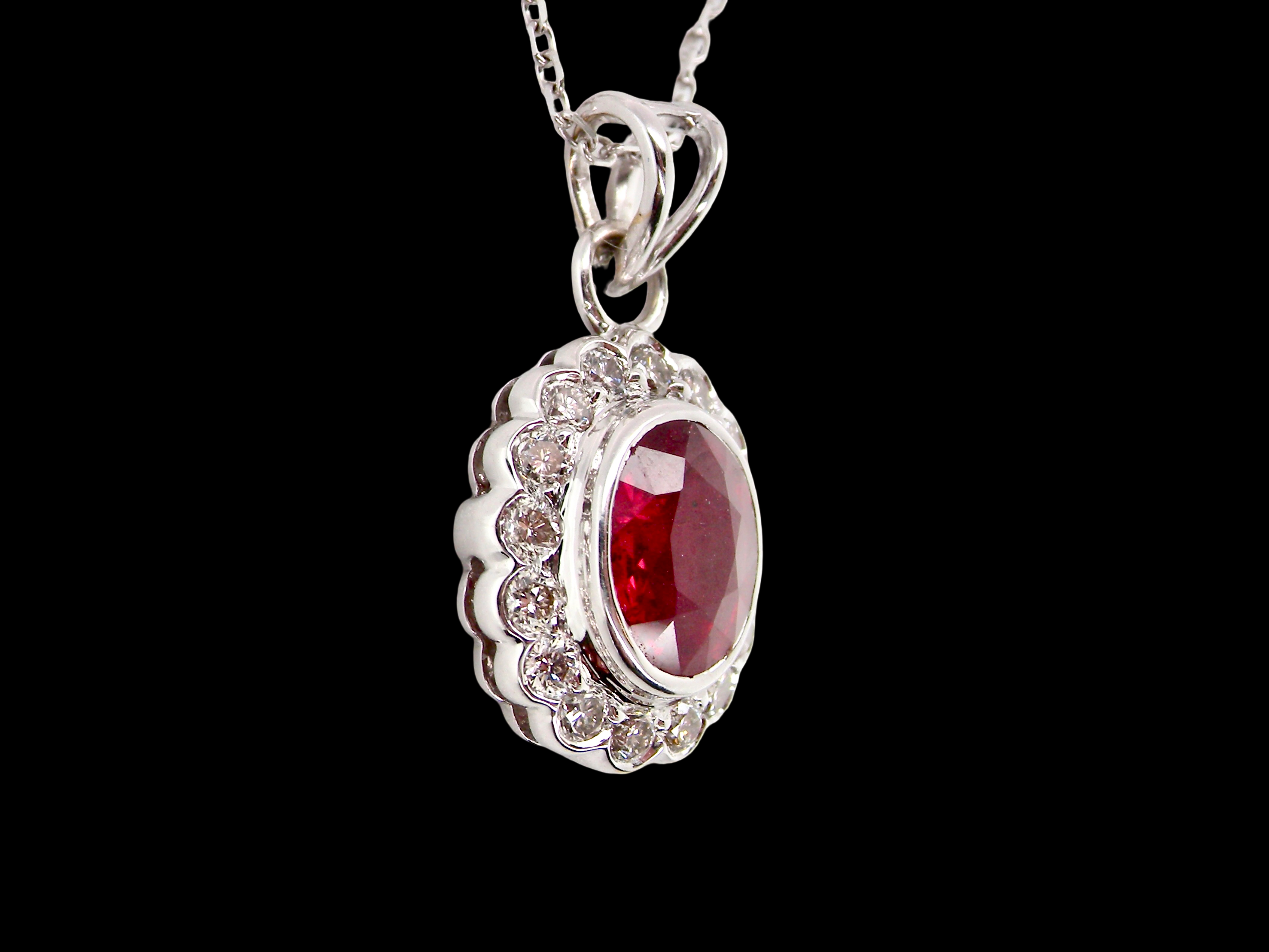 A fine white gold pendant that features to the centre an oval facet cut ruby, 8x6mm (est 1.25 carats) good deep red colour.
sidew
