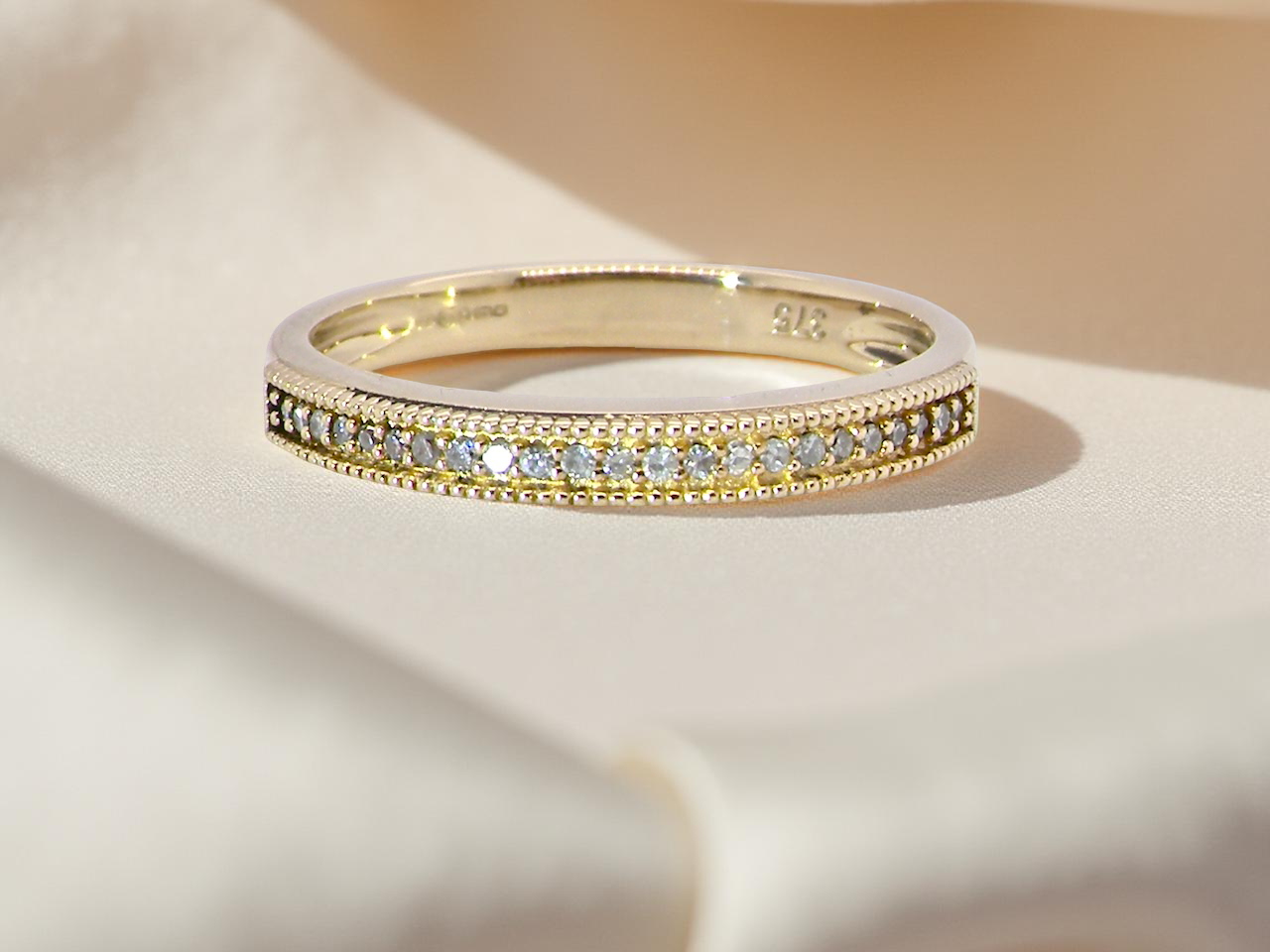 A half-hoop eternity ring set with approximately 24 white diamonds