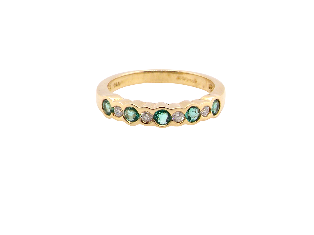 A half hoop eternity ring. Set with five round emeralds, each 3mm (0.10 carats) and set with an alternate brilliant cut white diamond, 2.4mm each (total 0.20 carats)
