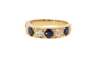 A yellow gold eternity ring featuring alternating round dark blue sapphires and clear round diamonds, shown on a plain white background.