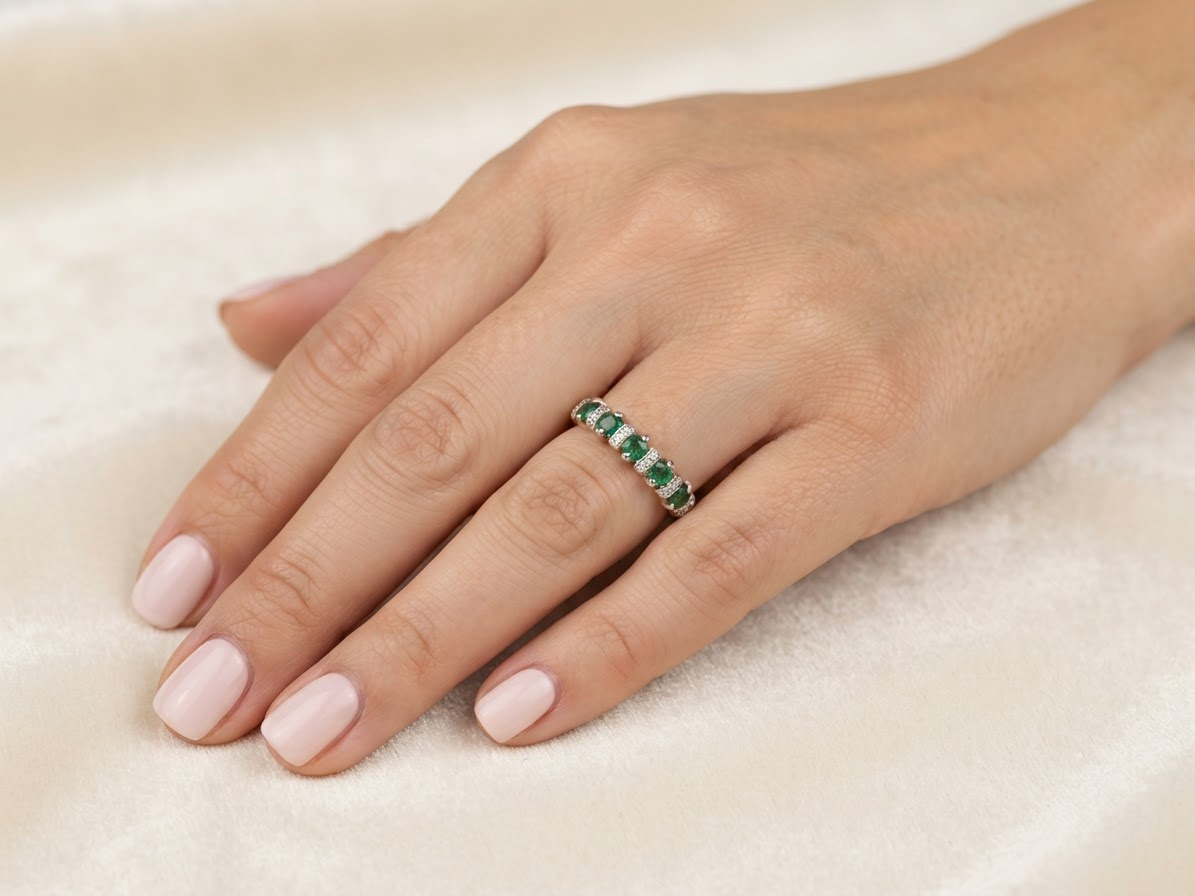hand A half hoop ring, stamped 750 (testing as 18 carat gold)&nbsp;

Set with alternate gemstones, five bright green emeralds