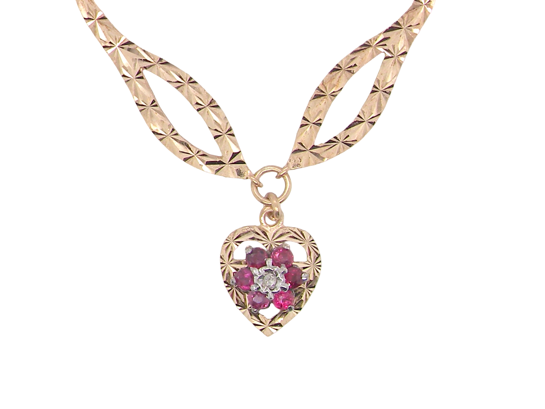 A late 1970s pendant/necklace. Features a heart shaped pendant that has a cluster set to its centre. Six small rubies 2.3mm each surround an illusion set diamond. 