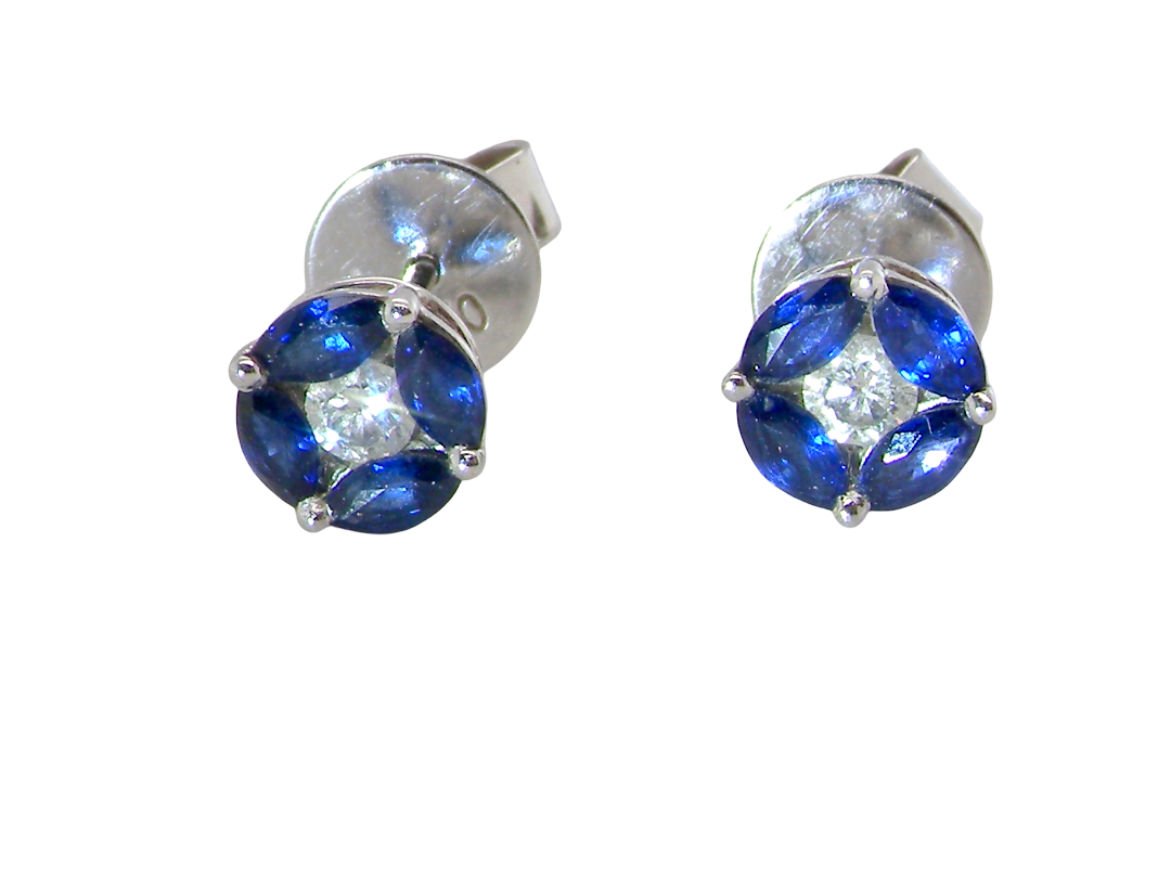 A pair of round stud earrings featuring deep blue gemstones in a four-petal arrangement with a clear center stone, set in silver-toned metal on a plain white background.