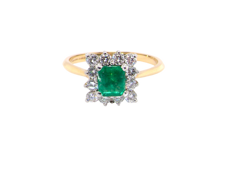 A lovely cluster ring that features to the centre a rectangle shaped emerald, 7x5mm. Shows a deep grass green colour which does have natural inclusions common with most emeralds, 