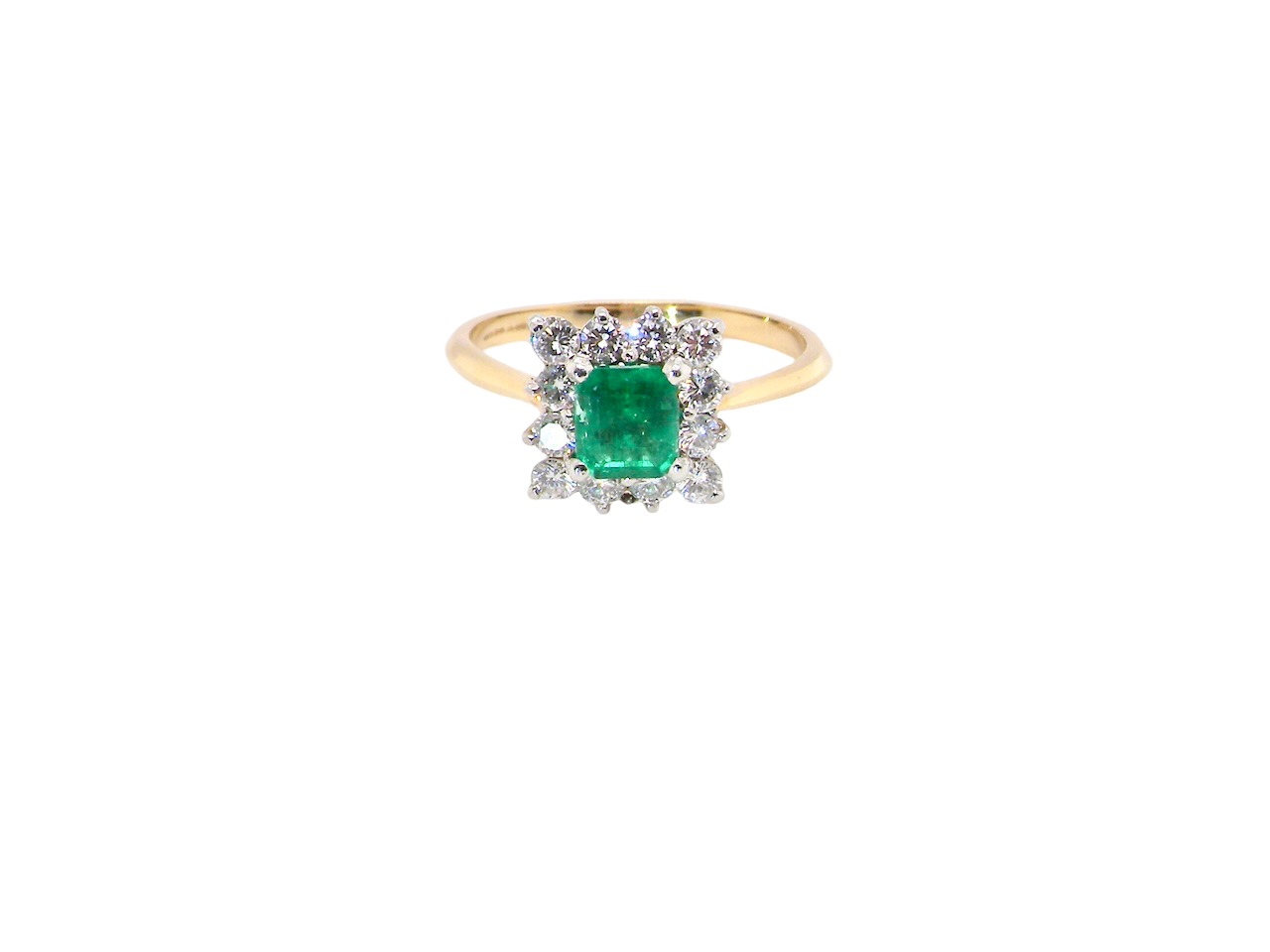 A lovely cluster ring that features to the centre a rectangle shaped emerald, 7x5mm. Shows a deep grass green colour which does have natural inclusions common with most emeralds, but the depth of colour is impressive.