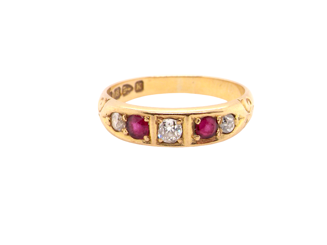 A vintage yellow gold ring featuring a row of round-cut pinkish-red rubies and clear diamonds, photographed on a solid white background.