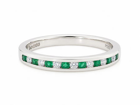 A ring featuring a channel setting of round-cut green emeralds and clear diamonds, shown on a plain white background.