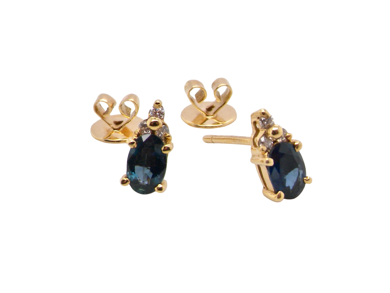 A pair of 18 carat gold earrings*. Set with a dark blue oval cut sapphire 6x4mm, claw set.

Above each, three small white diamonds, overall size 9x4.6mm, 
