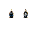 A pair of 18 carat gold earrings*. Set with a dark blue oval cut sapphire 6x4mm, claw set.

Above each, three small white diamonds, overall size 9x4.6mm, weight each 1 gram.
