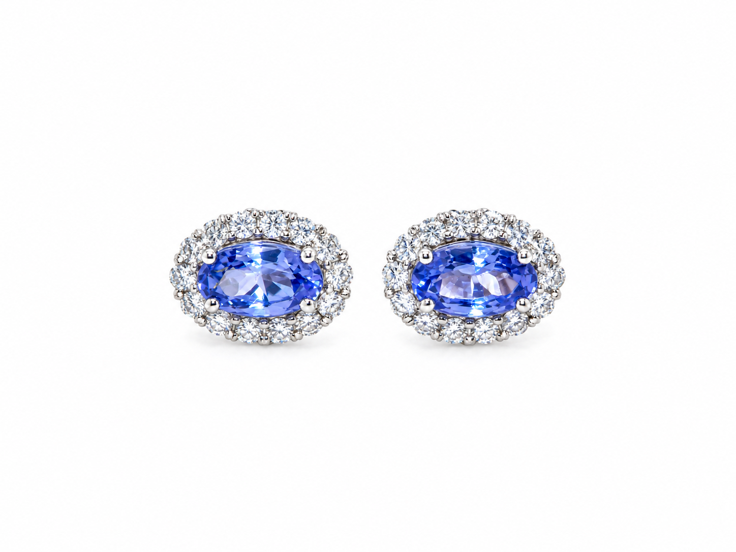 A pair of 18 carat white gold cluster earrings.&nbsp;

Features an oval tanzanite gemstone,