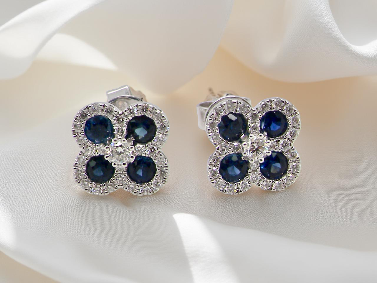 Pair of earrings with blue gemstones and clear stones on a white surface